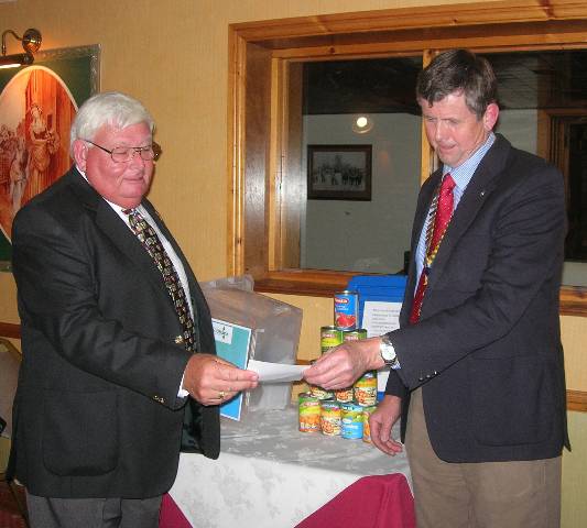 President Elfed Morris and Rotarian Brian Thomas (left) study the required food list.  The first items of food collected are on the table.