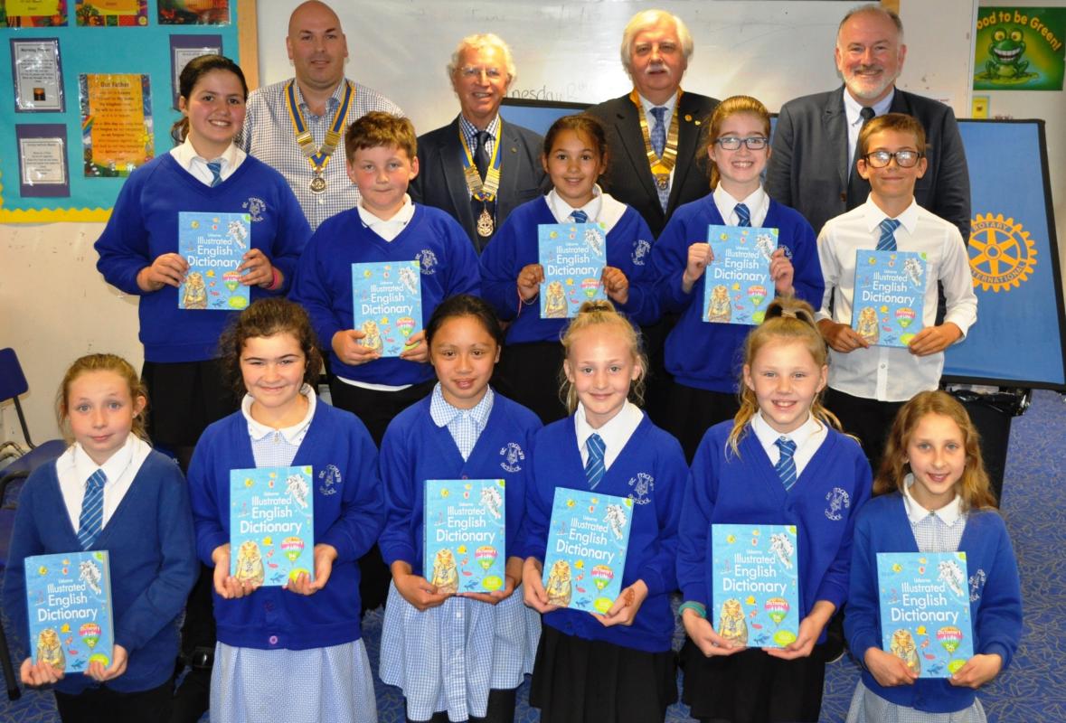 Rotary Presidents and children from St. Mary's RC School celebrate the arrival of the Dictionaries. L-R at back: Marc Pons -Burt (Ramsey), Howard Callow (Douglas), Paul Winnell (Rushen & Western Mann) and Kevin Kneen (Douglas).