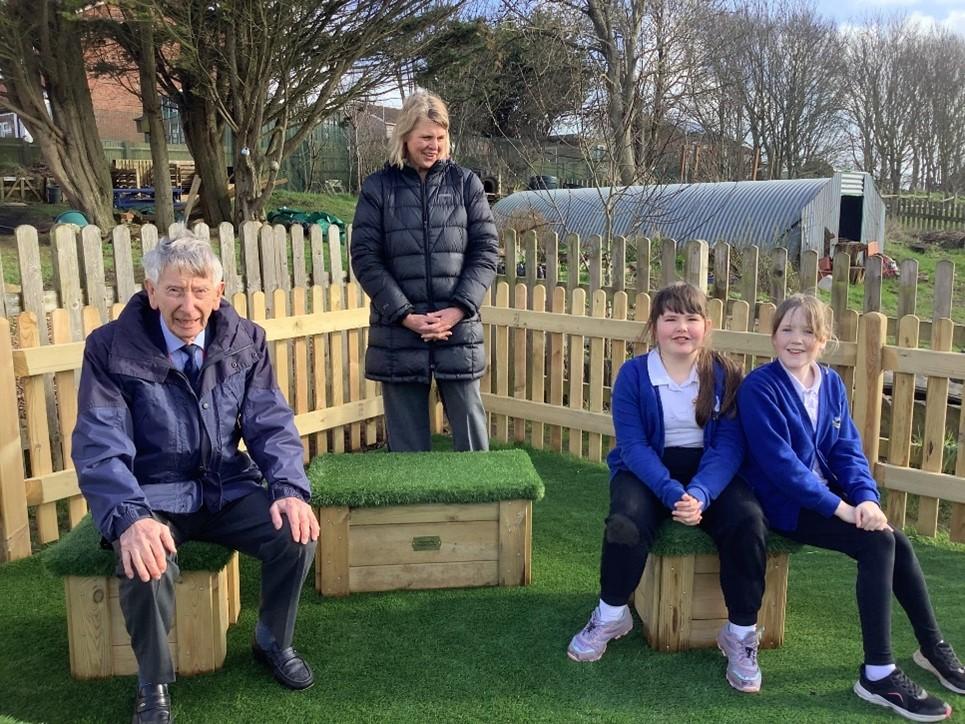 Jim Anderson putting one of the seats to good use at the opening of the new outdoor classroom and play area 