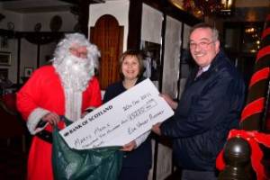 Audrey Lenaghen, President of Esk Valley Rotary Club, is ably assisted by Santa as she presents a cheque for £5220 to Mary's Meals representative Douglas Robertson.
