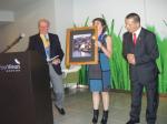 Vice President Ron Whitaker of Woodbridge presenting the picture of woodbridge to President of Machico Santa Cruz Marianna Afonso with Lourenco Basilico doing the translation
