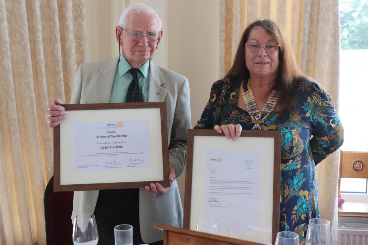President Mandy Davis presenting Keith Carlisle with a unique framed certificate to commemorate his uninterrupted 50 years of service, and a framed congratulatory letter from Gordon McInally, President Rotary International 2023/24.