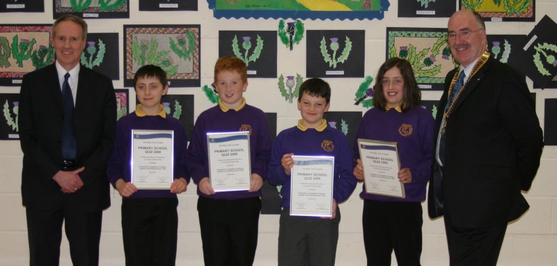 The photograph shows the winning team along with David Lynas, Head Teacher of Robert Owen Memorial Primary School, and Neil MacDonald, President of the Rotary Club of Lanark.