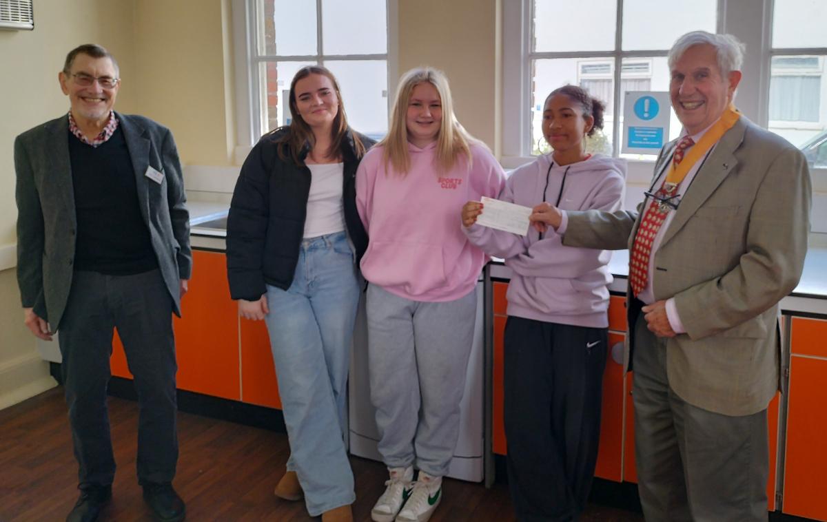 VP Clive Livingstone presenting the donation cheque to  Samantha Alvaraz Head of the Sixth Form, watched by two of the Sixth Form students and Tony Humphreys from the Martello Club