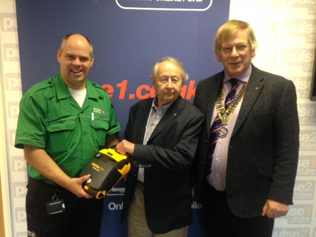 Last Year's President Barry Smith with Community Chair John Watson present the defibrillator.