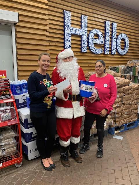 Santa receiving £100 donation from Tesco managers.