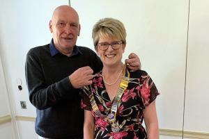 Retiring President Dave Griggfs hands over the Club's Chain of Office to Jo Banks