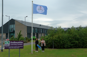 Beth and Georgia raise the Peace flag outside Dalbeattie Learning Campus