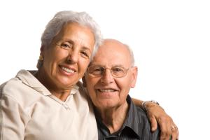 An elderly lady with her arm round the shoulder of an elderly gentleman.