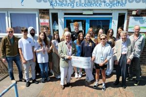 President Clive Livingstone presenting the donation to teacher Rebecca Fraser watched by students and teacher Donald McDonald (far left), Rotarian Jim Anderson (2nd from right) and Glenn Dakers from World Challenge 