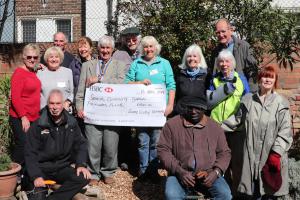 President Clive Livingstone presenting the grant cheque to Community Garden Chair Val Percival supported by other members of the Community Garden