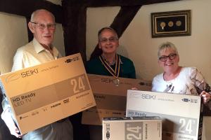 President Ian Haigh and John Neave handover the TVs to Jools Payne