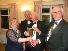 The photograph shows from L to R, District Governor Molly Youd, presenting the Wallesey Cup to founder members of The Rotary Club of Tywyn , Elwyn Price, Godfrey Worsey and President Anthony Pearson