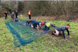 Competitors scrambling under a net under the watchful eye of 
Rotarian James Slinn