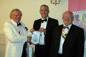Peter English, M.B.E. left, Stephen Barclay , centre, President Peter Bennett, right. Receives the Club Banner