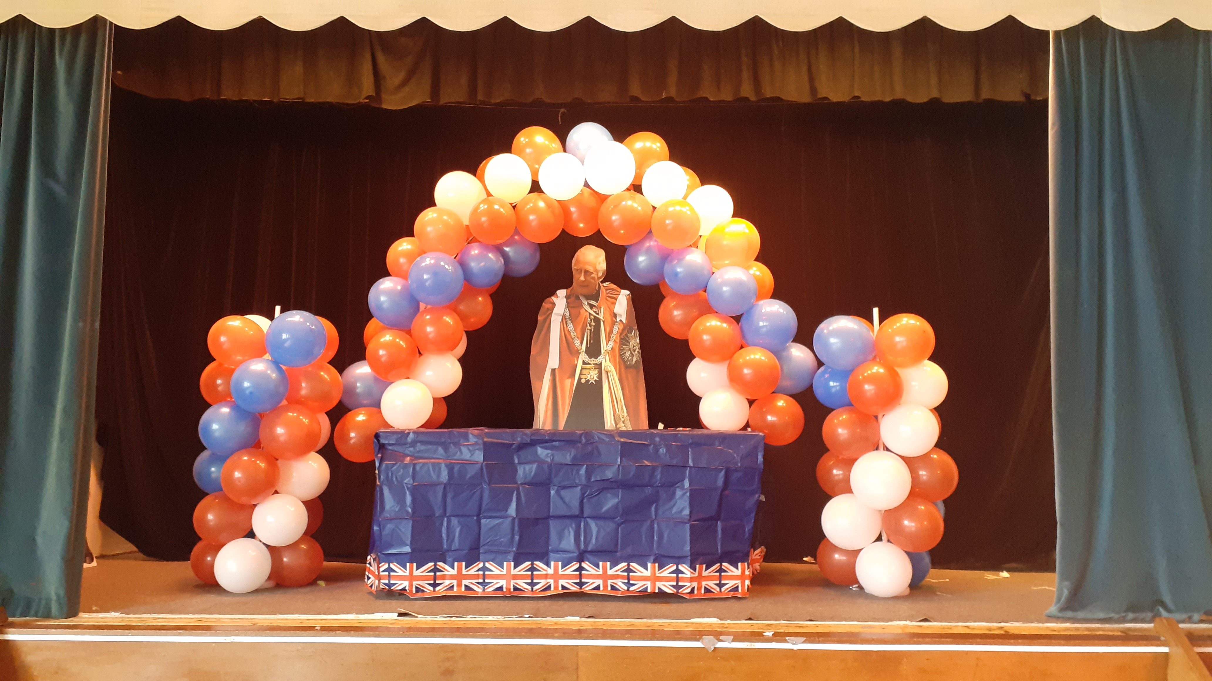 A person standing on a stage with balloonsDescription automatically generated with low confidence