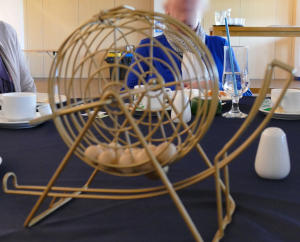 A hollow cage-like wooden wheel with wooden balls inside it