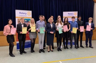 A row of young people holding certificates with a middle-aged woman in the middle