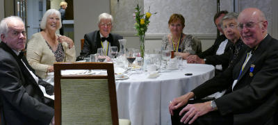 A group of people sitting around a dinner table at a black tie event
