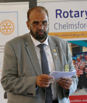 A bearded man with glasses standing in front of Club banners