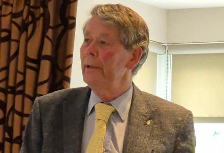 A gentleman wearing a light grey suit and a yellow tie