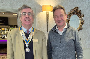Two men standing side by side, one wearing linen jacket and a President's chain of office and the other wearing a grey sweater