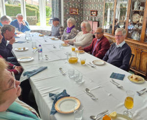 People sitting round a long dining table with place settings and glasses of orange juice