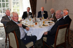Seven men sitting roud a dining table