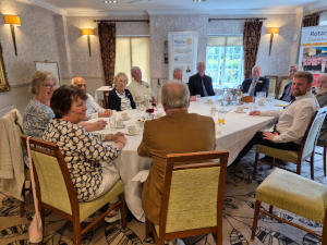 A group of people sitting round along dining table with oval ends