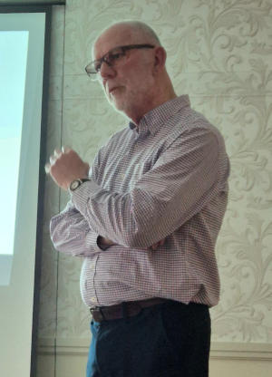 A balded and bearded white-haired man addressing an unseen audience