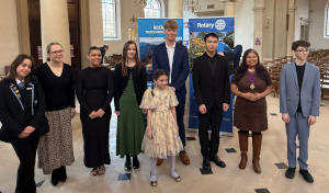 A group of oeople lined up in front of Rotary banners
