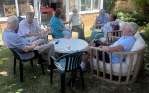 People sitting in comfortable chairss arond a garden table