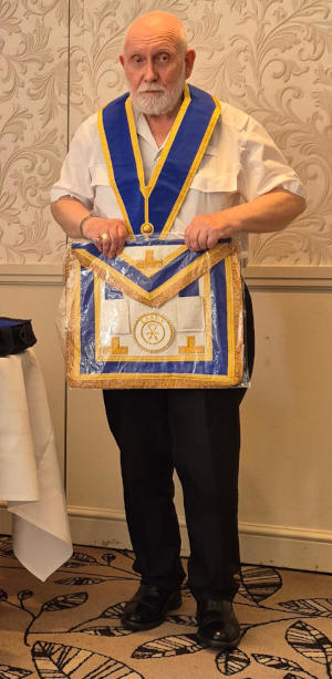 A bearded man wearing a Masonic collar and holding a Masonic apron