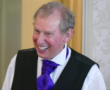 A smiling man wearing a waistcoat and a cravat