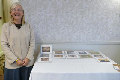 A woman with long silver hair standing next to a table with cards on it