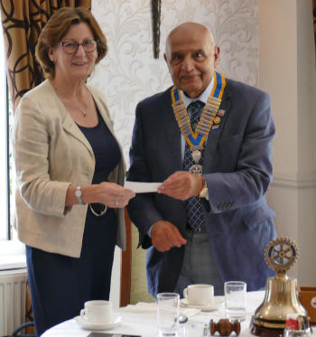 A woman with glasses being handed a cheque by a man wearing a chain of office