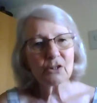 A lady with long grey hair and glasses