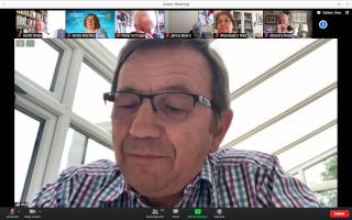 A bespectacled man speaking at a Zoom meeting
