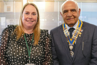 A woman with long light-brown hair standing next to a bald man wearing a chain of office