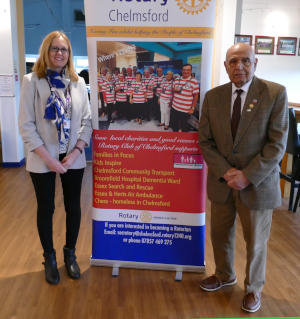 A woman and a man standing either side of a Rotary pull-up banner