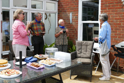 Four people chatting near a buffet table outside a house