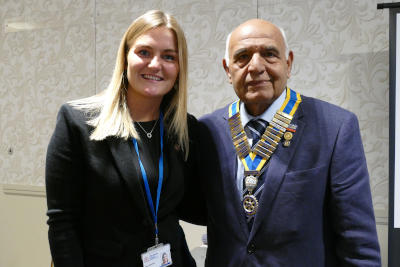 A blonde woman next to a man wearing a chain of office