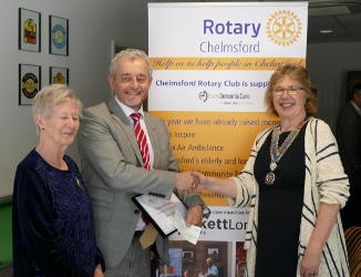 Two women and one man in front of a Rotary banner