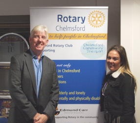A man and a woman standing either side of a Rotary Club banner