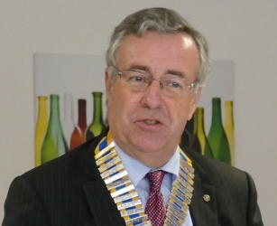 A man wearing glasses and a chain of office