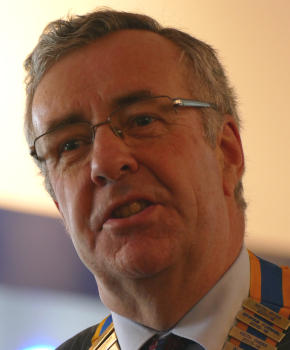 A man with wavy brown hair and glasses