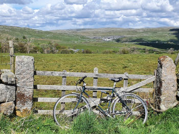 A bicycle leaning against a gate in a stone wall