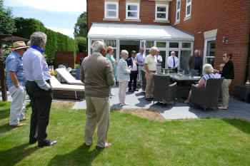 People wearing summer clothing in the garden of a large house