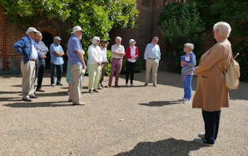 A group of people standing in the sun listening to a guide