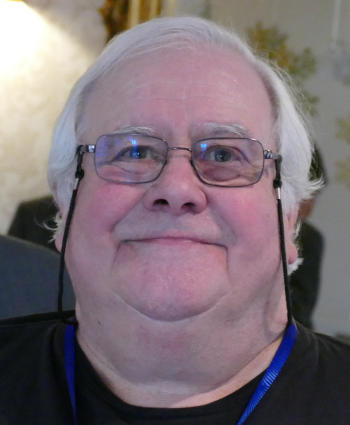 A man with white hair wearing glasses